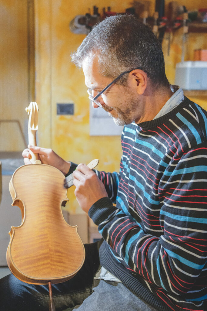 Marco vernicia un violino destinato al noleggio